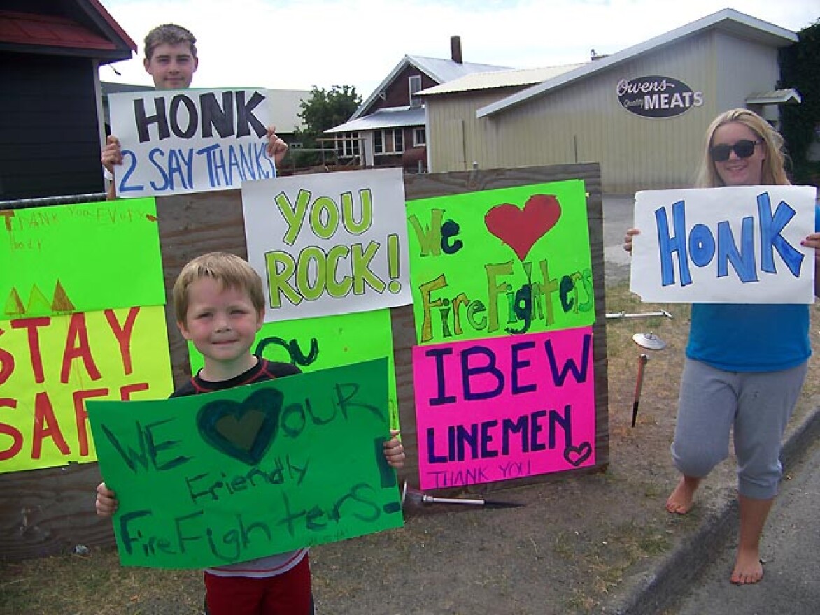 Chase Stanley, 15, of Cle Elum, and his siblings wave to passing motorists with signs supporting the firefighters at the Taylor Bridge Fire in central Washington. Photo by Anna King